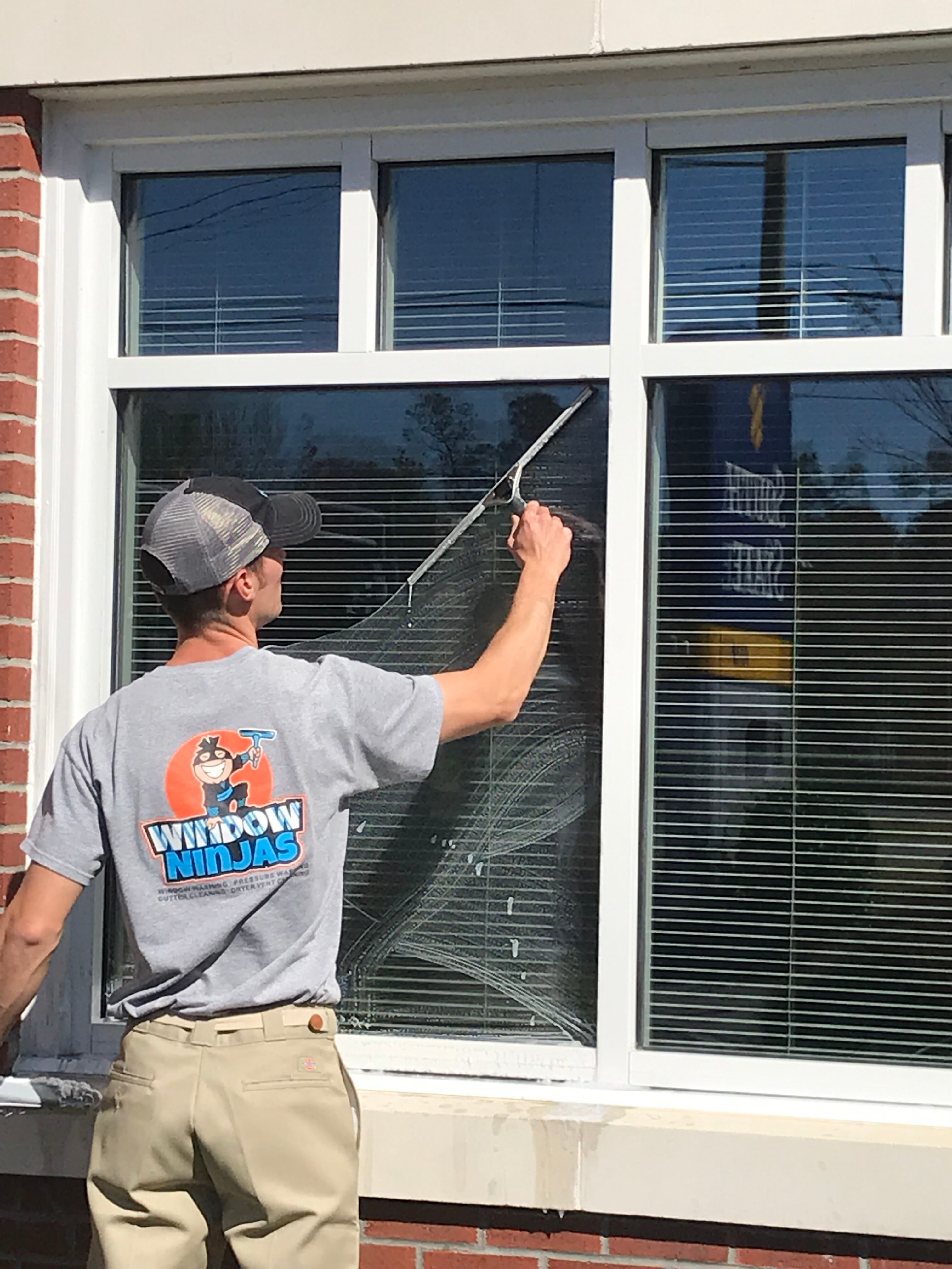 An image of a window getting cleaned with Window Ninjas power washing.